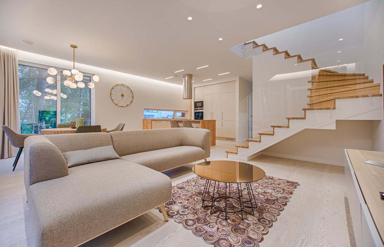 about-01 Contemporary living room with neutral tones, a sleek sofa, and elegant wooden staircase.